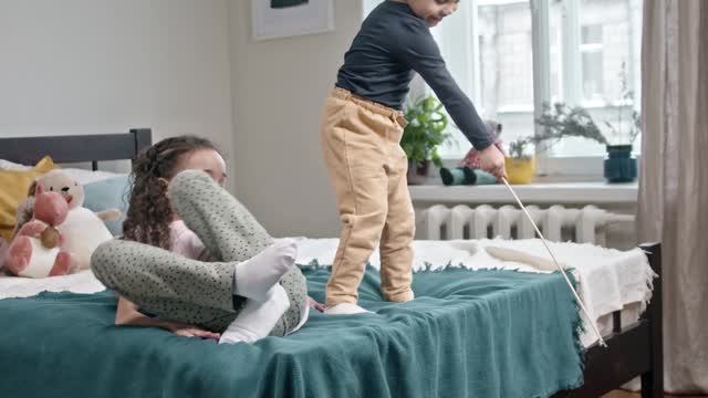 Kids Playing Catch The Bait With Their Cat In The Bedroom