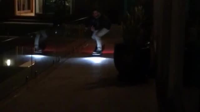 Guy on skateboard with nights at night falls as he gets closer to camera