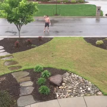 Shirtless guy showers in rain in middle of street