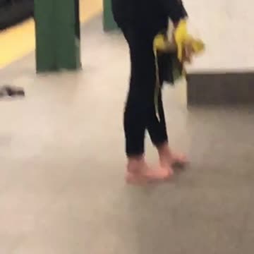 Girl stands inside subway station with no shoes