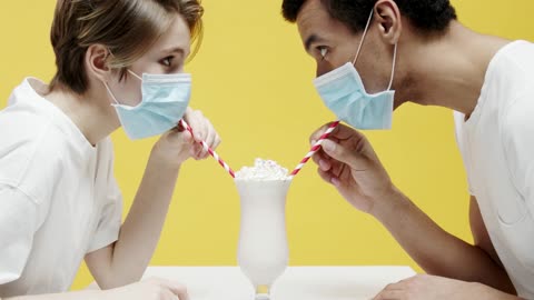 A Couple Wearing Masks, Sharing A Glass Of Milkshake