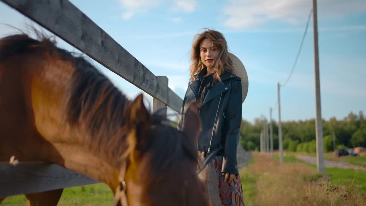 Stylish female posing near grazing horse