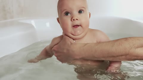 Happy baby being bathed by his mother