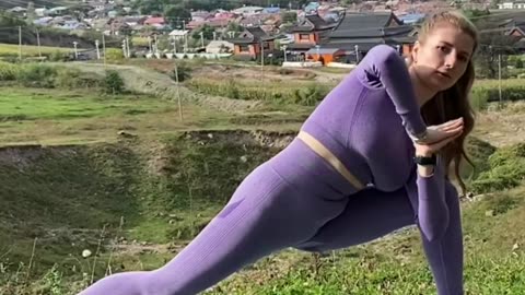 Doing yoga outdoors in a purple bodysuit