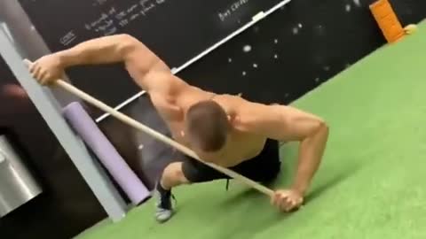 Man Performs Pushups While Balancing With Stick