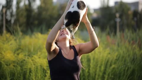 Woman beautiful young happy with long dark hair holding small dog in the garden