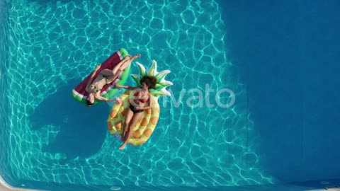 Pool with two girls lying on floats