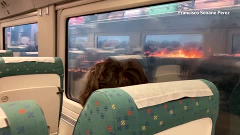 Passengers look on as wildfire rages near stuck train