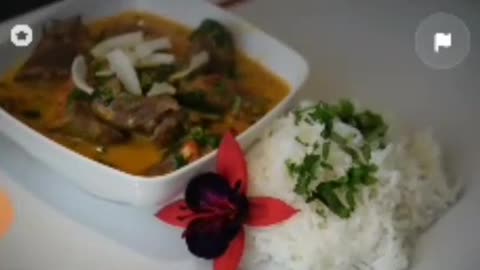 Very delicious Thai meat curry with plain rice with coriander on it decorated with red flower