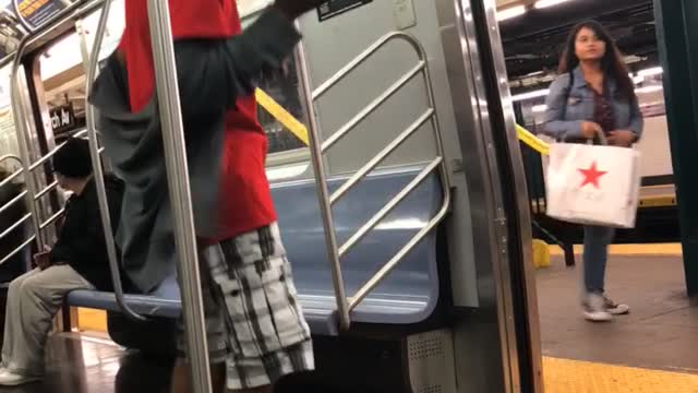 Man in red and flannel shorts dances on subway