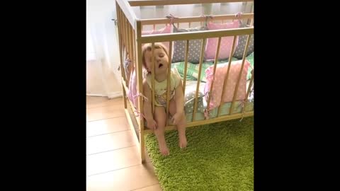 Cute baby is leaning his head on the crib and dozing