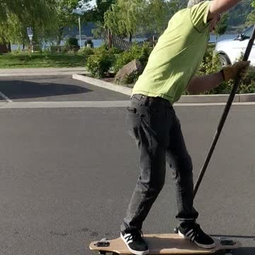 Guy green shirt rowing down street on longboard skateboard