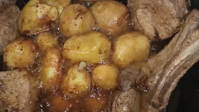 Cooking pork steaks with potatoes in a cauldron.