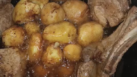 Cooking pork steaks with potatoes in a cauldron.