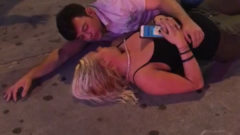 Guy laying on sidewalk with girl outside club