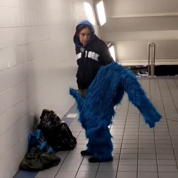 Woman putting on furry blue costume onesie