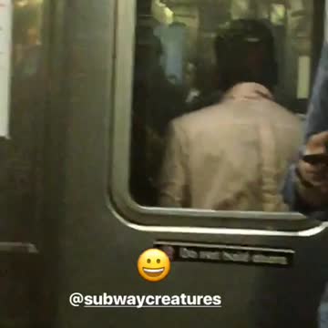 A man in a pink shirt dancing in between subway cars