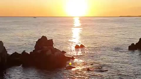 The hot sun. Bright sunrise. The sea and rocks.