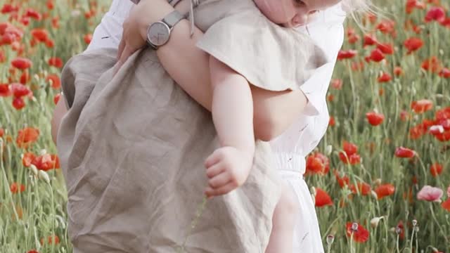 woman-carrying-her-baby-while-standing-on-red-poppy-flower-field