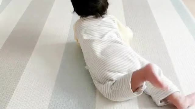 A baby crawling for a baby bottle