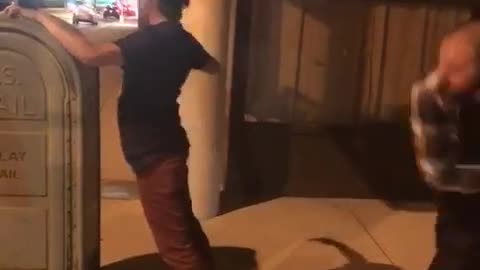 Guy in black shirt getting hit with belt on the street