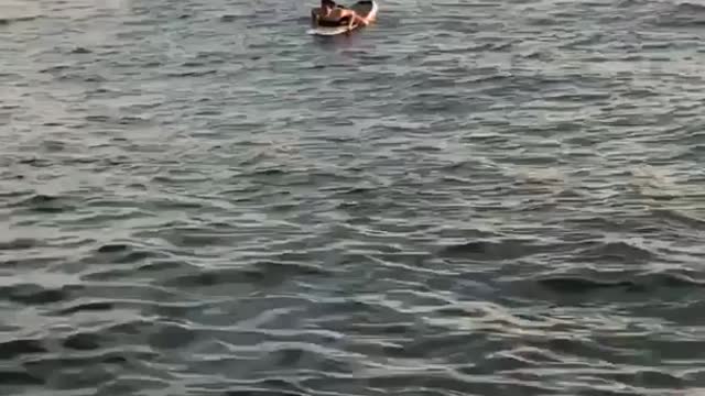 Guy swimming on surfboard in water