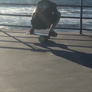 Man balancing on cylinder on pier looking at ocean