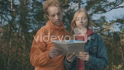 Young female and male hikers looking at a map outdoors