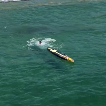 Guy yellow surfboard paddle white shirt falls into water ocean