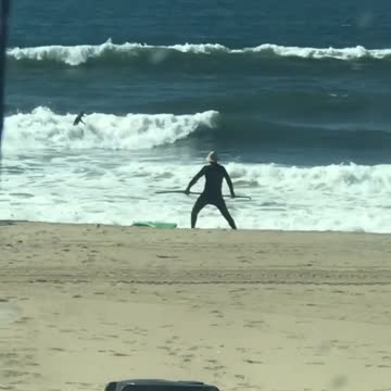 Guy with paddleboard does stretches at the beach with his paddle
