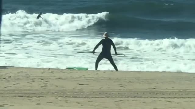 Guy with paddleboard does stretches at the beach with his paddle