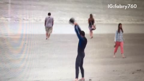 Guy black wetsuit lifting weights at beach