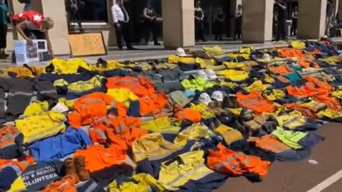 Lavoratori australiani stendono le uniformi di lavoro sui gradini del parlamento.