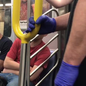 Person on subway with purple gloves holding onto pole