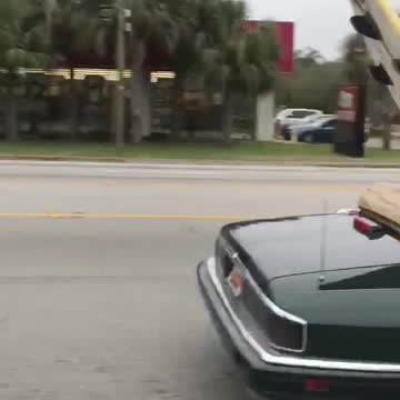 Black topless car drives down highway with unsecured wood board