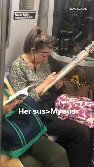 Woman cross stitching on subway train holds frame with a string tied to her ear