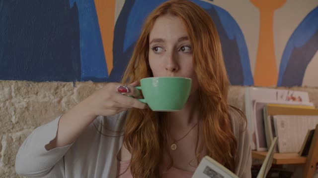 Young woman drinking coffee and reading