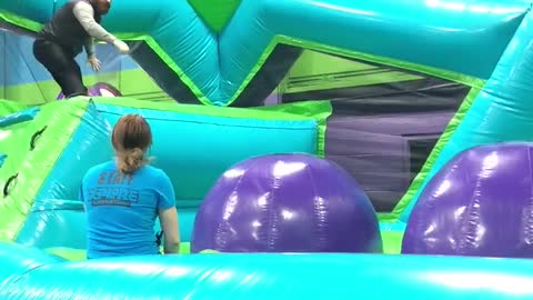 Grown man trampoline obstacle course slips on purple ball