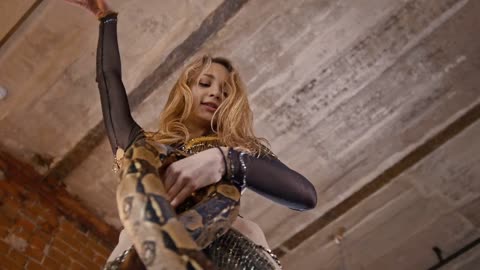 Female circus actress dancing with a snake in a studio