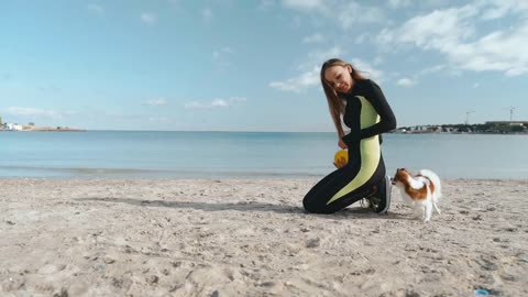 Young adult athletic woman spending day on beach with little dog