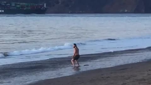 Shirtless man black shorts on shore doing exercise routine