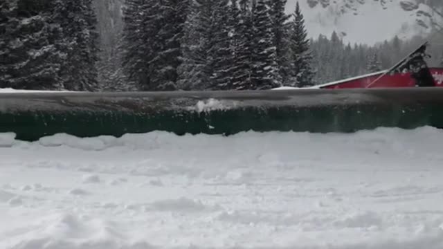 Skier with helmet goes downhill on ramp and ends up falling down