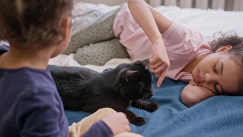 Kids Petting Their Cat On The Bed