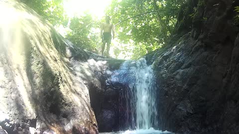 Kid takes a while to jump off of small waterfall and ends up slipping in instead