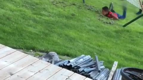 Kid red shirt tries to jump onto outdoor hammock faceplants into grass