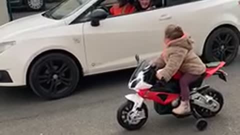 Kid on Toy Motorbike Challenges Driver to a Race