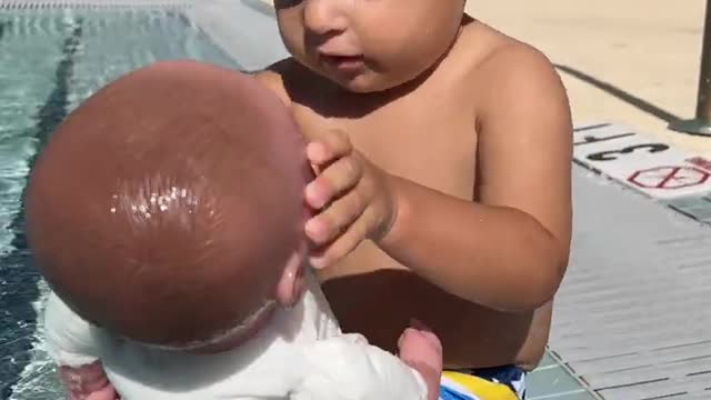 Little Baby David playing with doll in the pool. Funny Baby Game