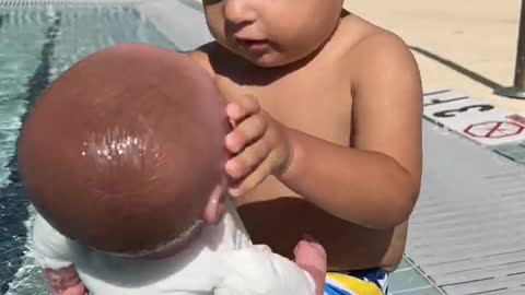 Little Baby David playing with doll in the pool. Funny Baby Game