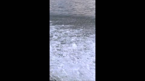 Trail on blue water surface behind of fast moving ferryboat