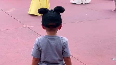 4-year-old boy tips his hat to Disney princesses during parade.